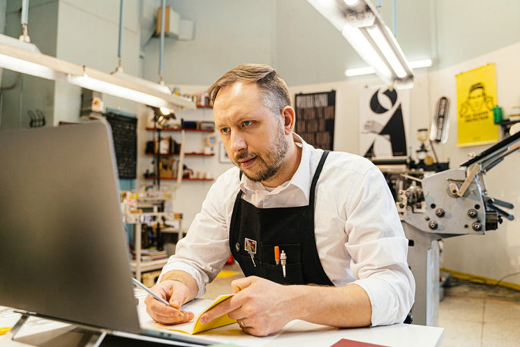 A man in a printing shop using a computer